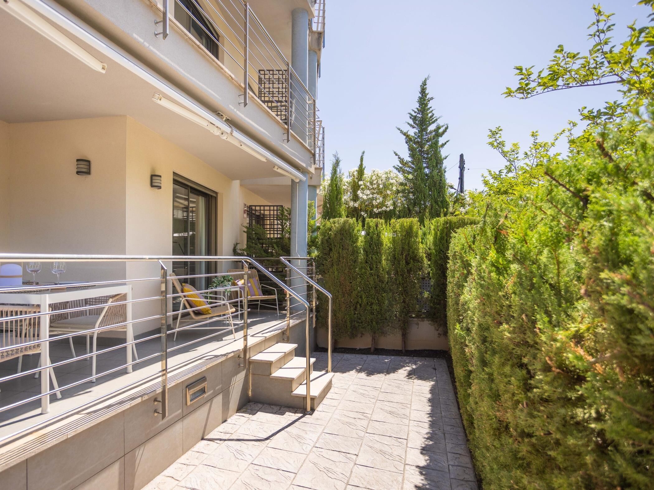 A balcony with outdoor seating and a staircase leading to an upper floor.