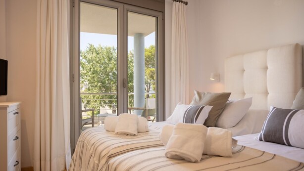 Une chambre d’hôtel avec un grand lit, un téléviseur posé sur une commode et un balcon donnant sur la forêt.