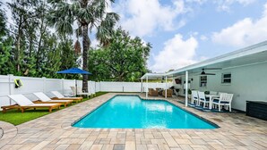 A swimming pool with lounge chairs and a covered patio area. - Coastin Close Family Fun HTD Pool Outdoor Games (Pinellas Park)