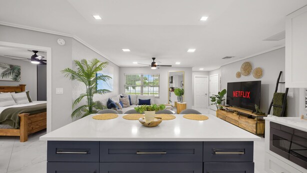A modern kitchen with a large island, built-in appliances, and a flat-screen TV displaying 'NETFLIX'. - Coastin Close Family Fun HTD Pool Outdoor Games (Pinellas Park)