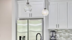 A kitchen with a modern design, featuring a double sink, a blender, and two hanging pendant lights.