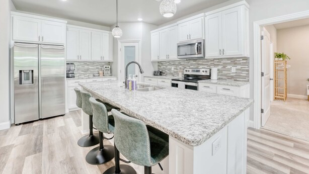 A modern kitchen with white cabinets, a granite countertop, and stainless steel appliances.