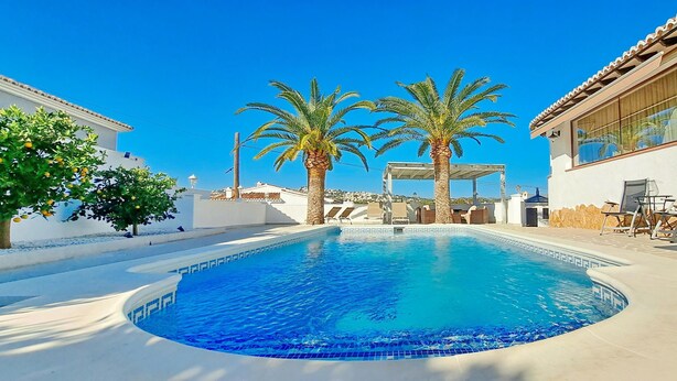A swimming pool with two palm trees, a covered area, and a building with outdoor seating. - Villa Esmeralda by Solidays - Moraira, Costa Blanca (Moraira)