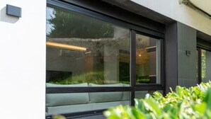 A modern building with large windows and a view of greenery outside. - Diseño y confort en Via Cornelia (Santander)