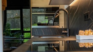 A modern kitchen with a sleek design, a built-in oven, and a large window overlooking a garden. - Diseño y confort en Via Cornelia (Santander)
