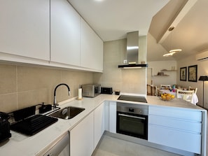 A modern kitchen with white cabinetry, a built-in oven, and a microwave.