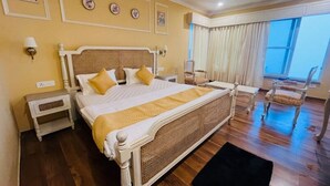 A bedroom with a large bed, bedside tables, a chair, and a window with curtains. - The Taal Cottage (Bhimtal)