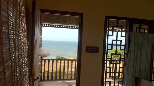 A room with a view of the ocean through a door with a decorative grille. - Joppa House (Nagercoil)