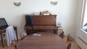 A dining area with a round wooden table, chairs, a wooden cabinet, and a radiator.