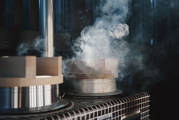 Un contenedor metálico que emite vapor, probablemente parte de un sistema de calefacción, con una rejilla metálica debajo.