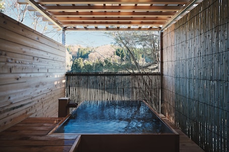 A wooden spa with a hot tub, wooden walls, and a bamboo fence.