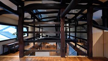 A multi-level wooden interior with a staircase, wooden beams, and a view of the outside.