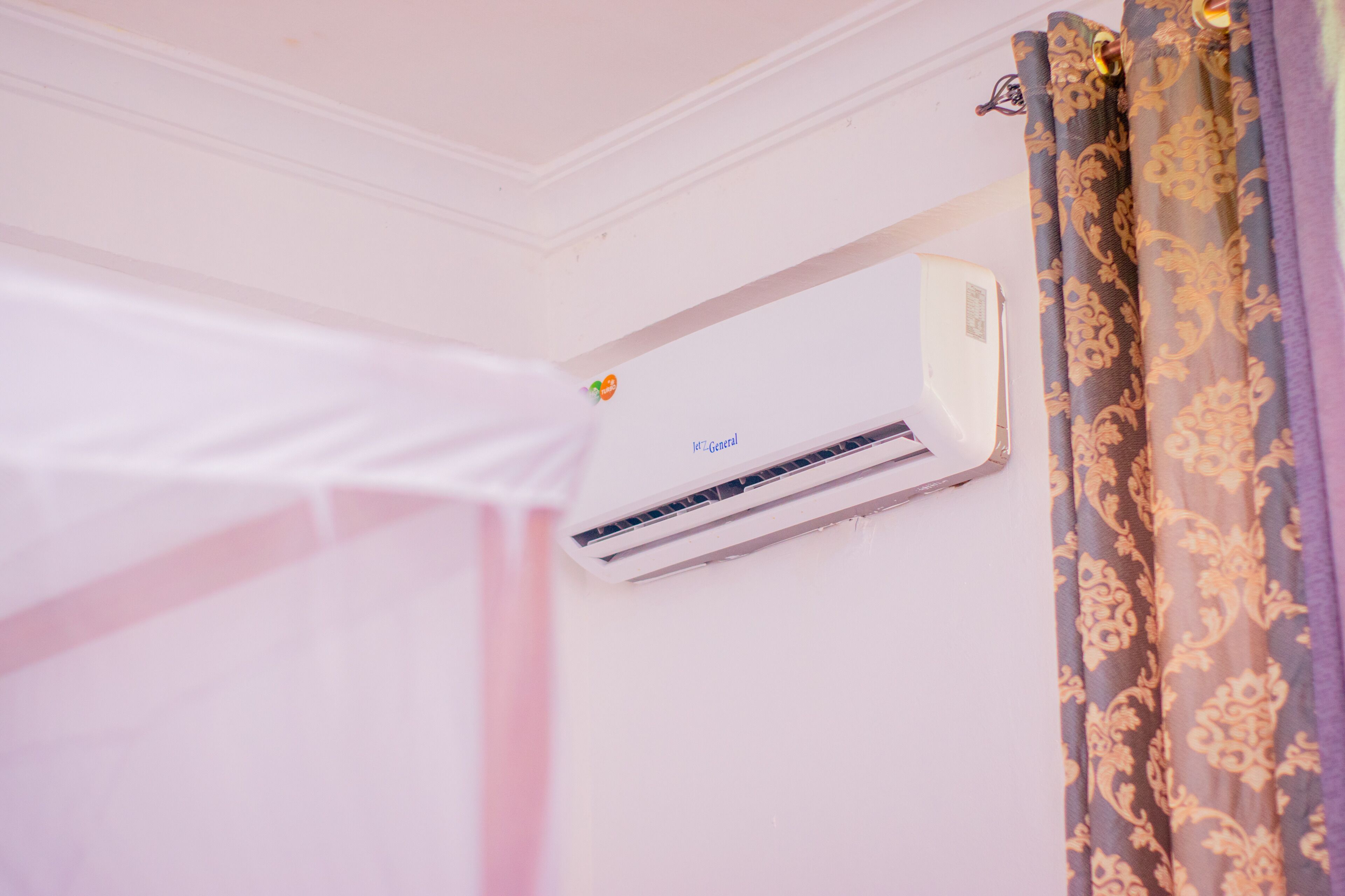 Et værelse med aircondition i loftet og et gardin med blomstermønster.