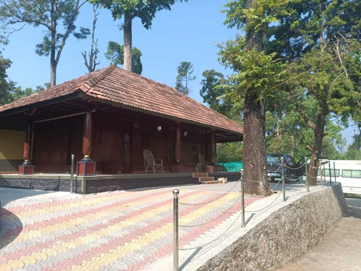 A covered outdoor seating area with a tiled floor, wooden benches, and a stone wall.