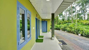A corridor with blue-framed doors, a tiled floor, and potted plants along the side.