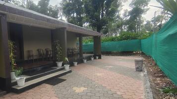 A covered outdoor seating area with chairs and potted plants.