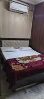 Una cama con una colcha estampada, un cabecero y un equipo de aire acondicionado montado en la pared.