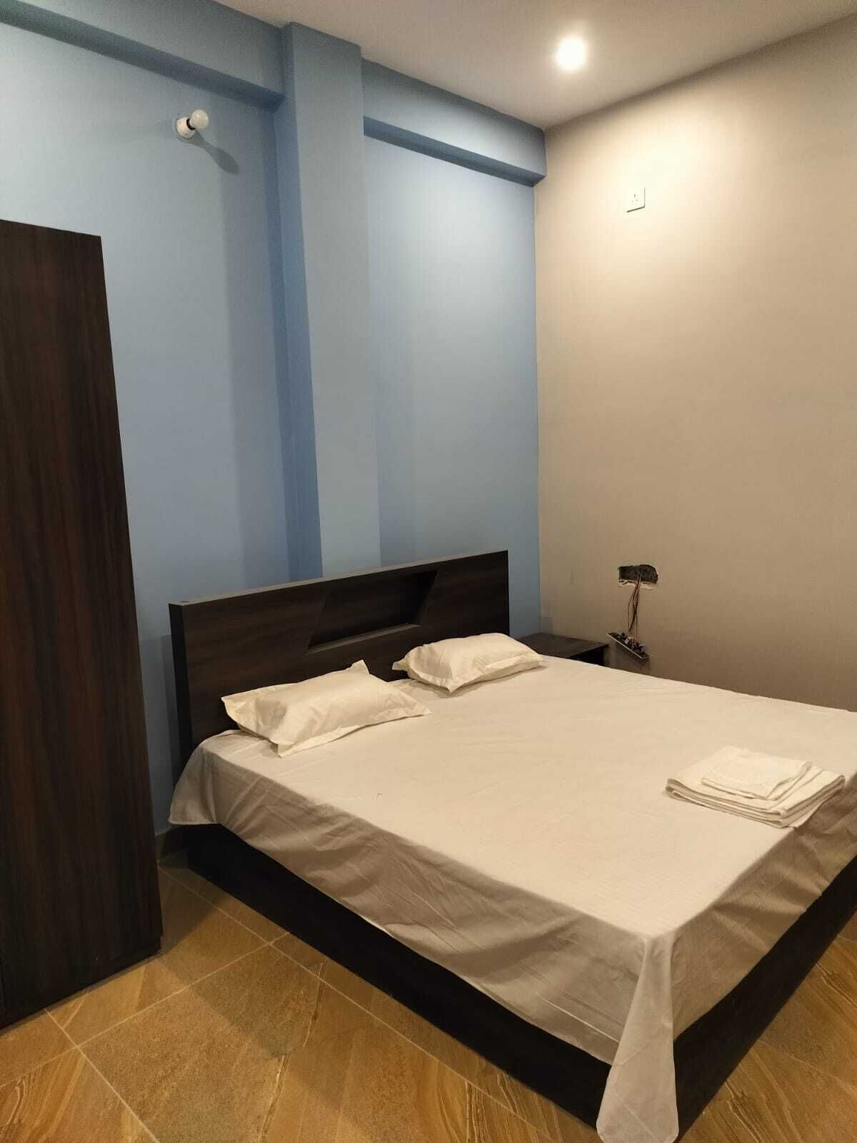 Una cama bien hecha con ropa de cama blanca en una habitación con paredes azules y suelo de madera.