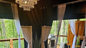 A spa area with a hot tub, a wooden table with snacks, and a view of the outdoors. - Adults only, Honeymoon Cabin with view, Covered Hot Tub, Fireplace, & TV. (Wellington)