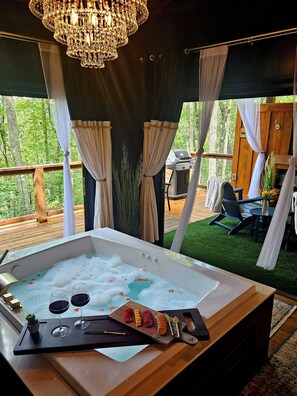 Area benessere con vasca idromassaggio, un tavolino con snack e vista sull'esterno.