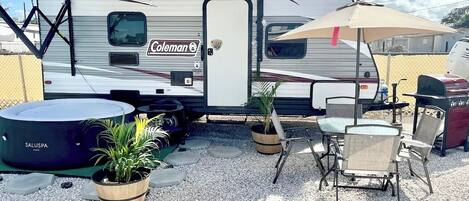 A Coleman RV with a covered patio area featuring outdoor furniture and a grill.