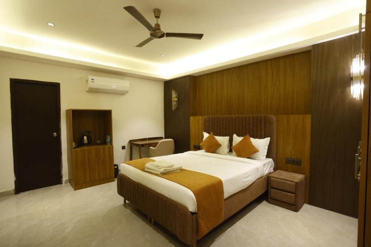 A hotel room with a bed, bedside table, wardrobe, and ceiling fan.