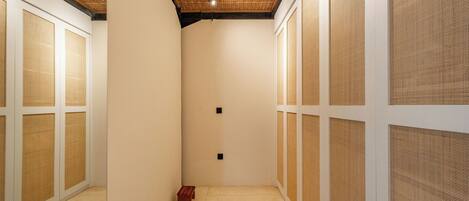 Un couloir étroit avec un plafond en bois, des murs blancs et un petit tabouret en bois.
