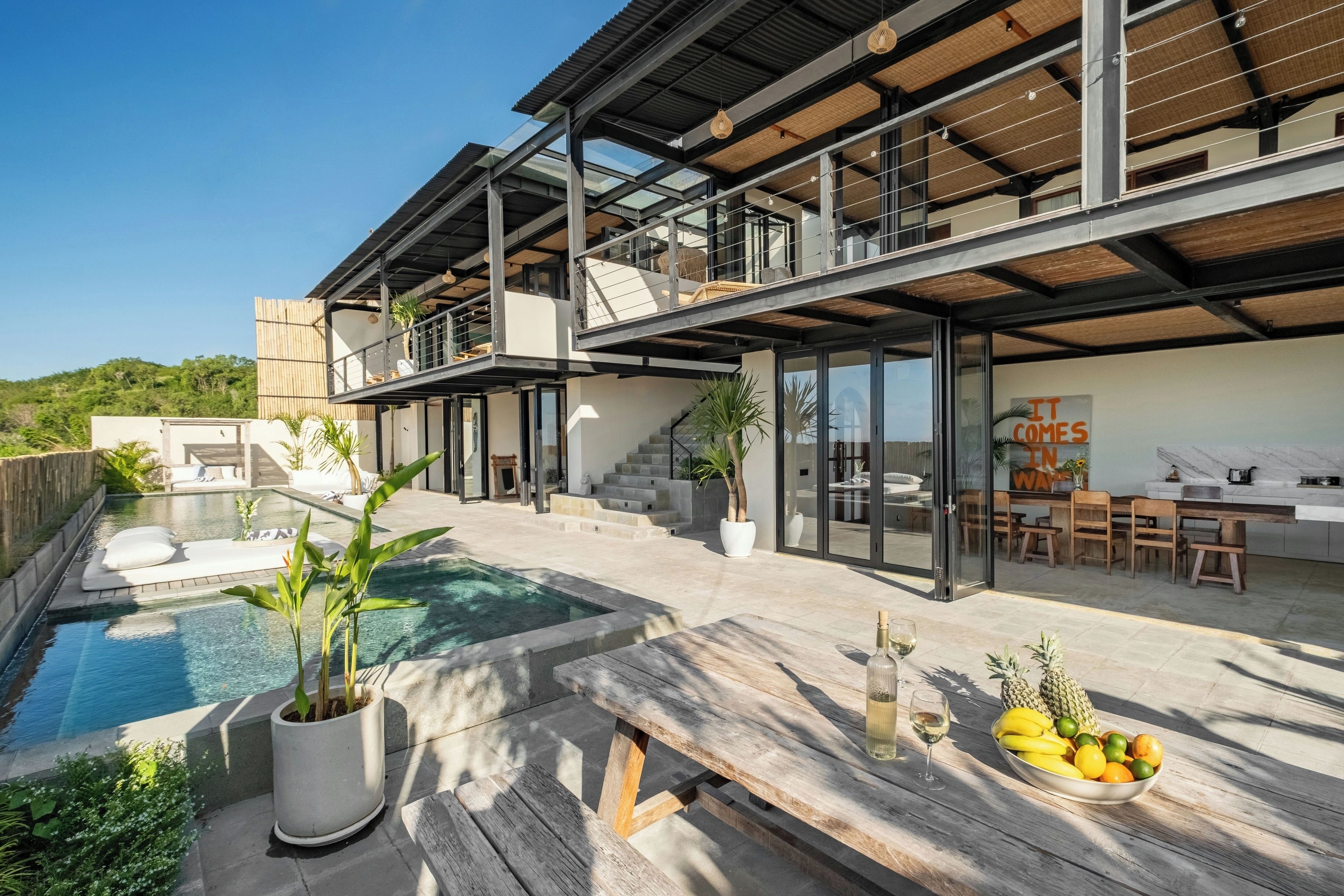 Et moderne hus med swimmingpool, udendørs siddepladser og spiseområde.