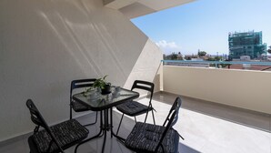 Ein Balkon mit Tisch und Stühlen, einem Blumentopf und Blick auf eine Baustelle.