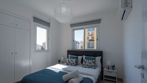 Ein Schlafzimmer mit einem Bett, einem Nachttisch, einem Fenster und einer Klimaanlage.