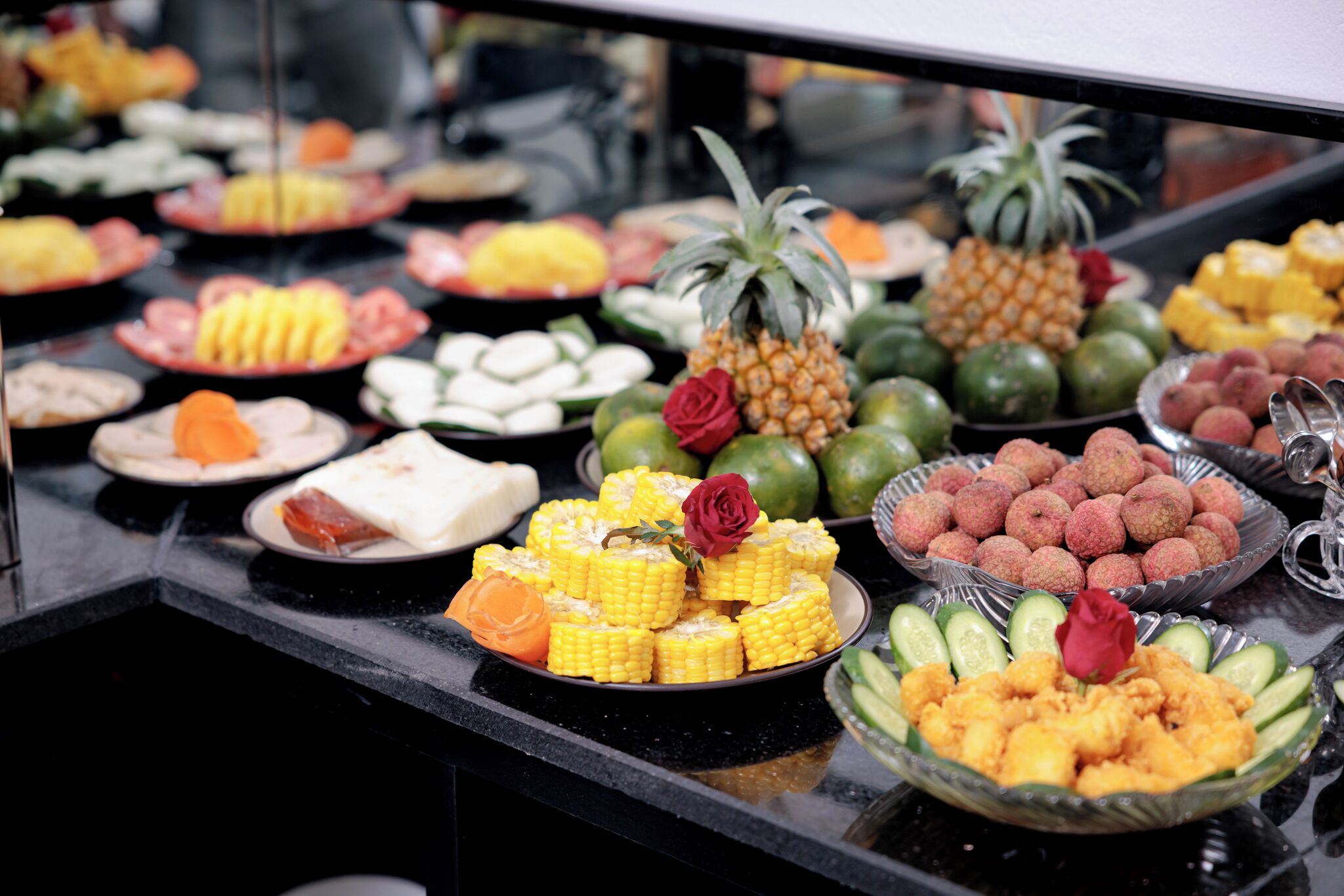 Ein Buffet mit verschiedenen Speisen, darunter Mais, Ananas sowie andere Früchte und Gemüse.