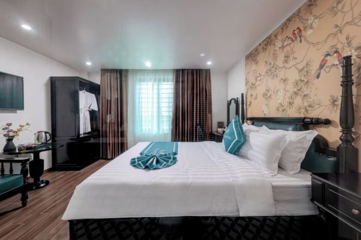 A hotel room with a bed, a desk, a chair, a TV, and a window with curtains.