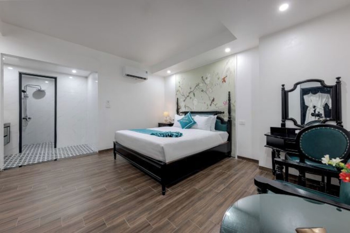 Une chambre moderne comprenant un lit, une coiffeuse avec un miroir et un espace douche.