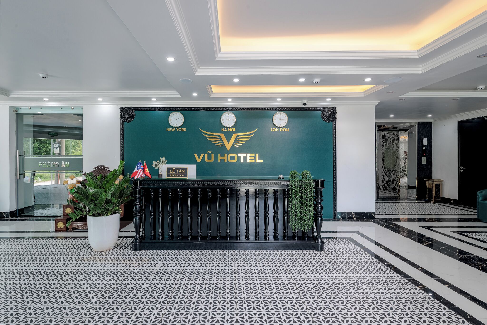 Zona de recepción con un mostrador negro, un reloj y un cartel con el nombre del hotel.