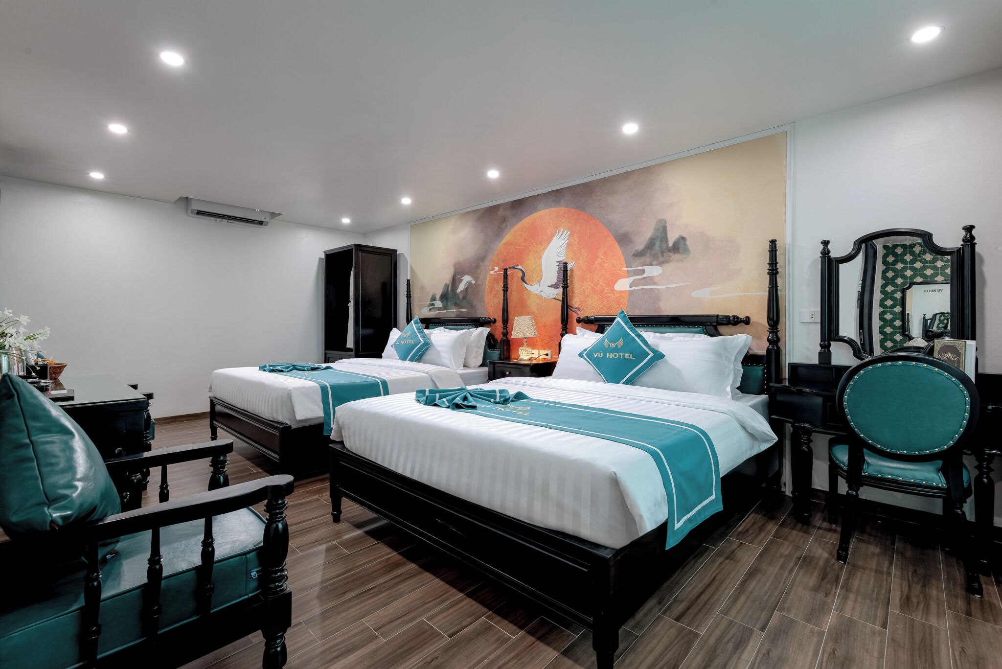 Una habitació d'hotel amb dos llits, un mural gran, un mirall i un terra de fusta.