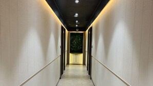 A corridor with a tiled floor, walls with a textured finish, and recessed lighting. - Hotel Royal Nest (Ajmer)