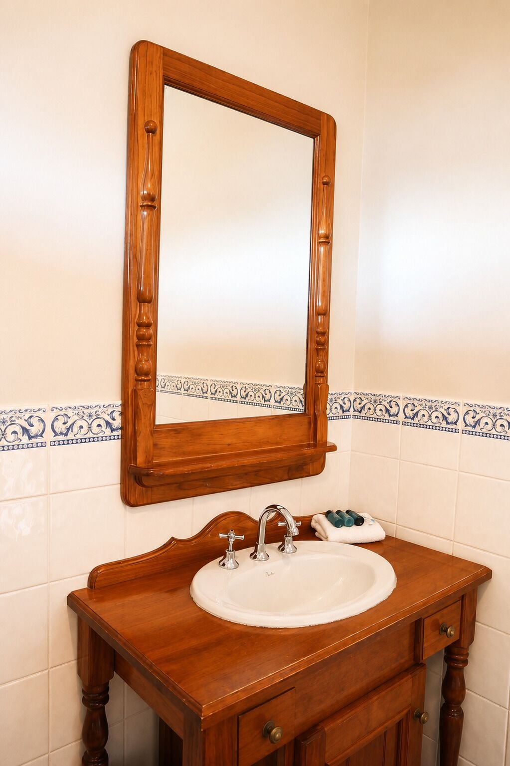 A bathroom with a wooden vanity, a white sink, a mirror, and decorative blue and white tiles.