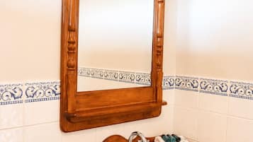 A bathroom with a wooden vanity, a white sink, a mirror, and decorative blue and white tiles.