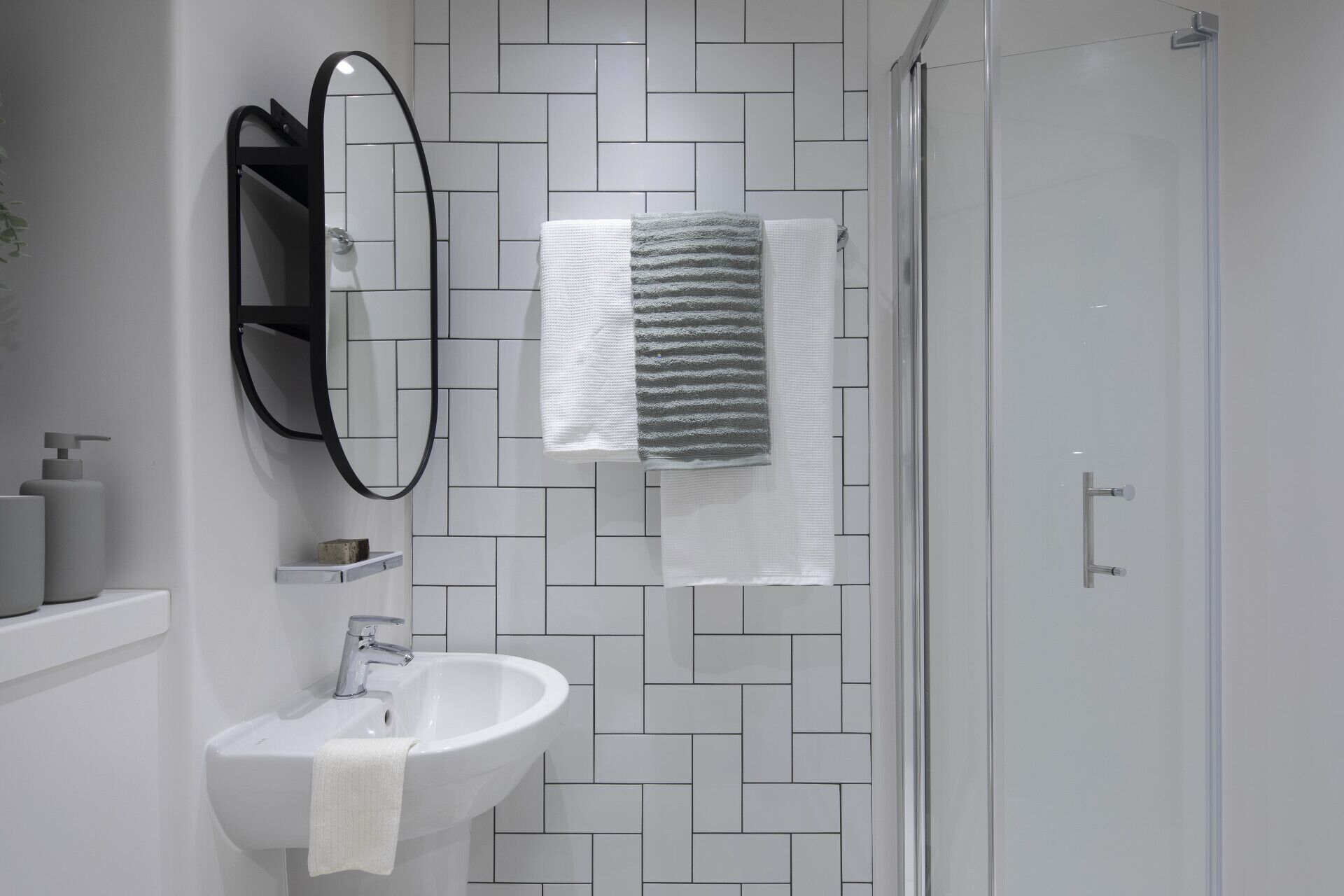 A bathroom with a white sink, a mirror, and a shower.
