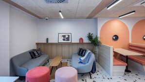A modern lounge area with seating, a small table, and a ceiling fan. - Modern Studios with Kitchen & Ensuite (Edinburgh)