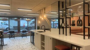 A modern kitchen with a bar area, a large window, and a seating area with stools. - Modern Studios with Kitchen & Ensuite (Edinburgh)