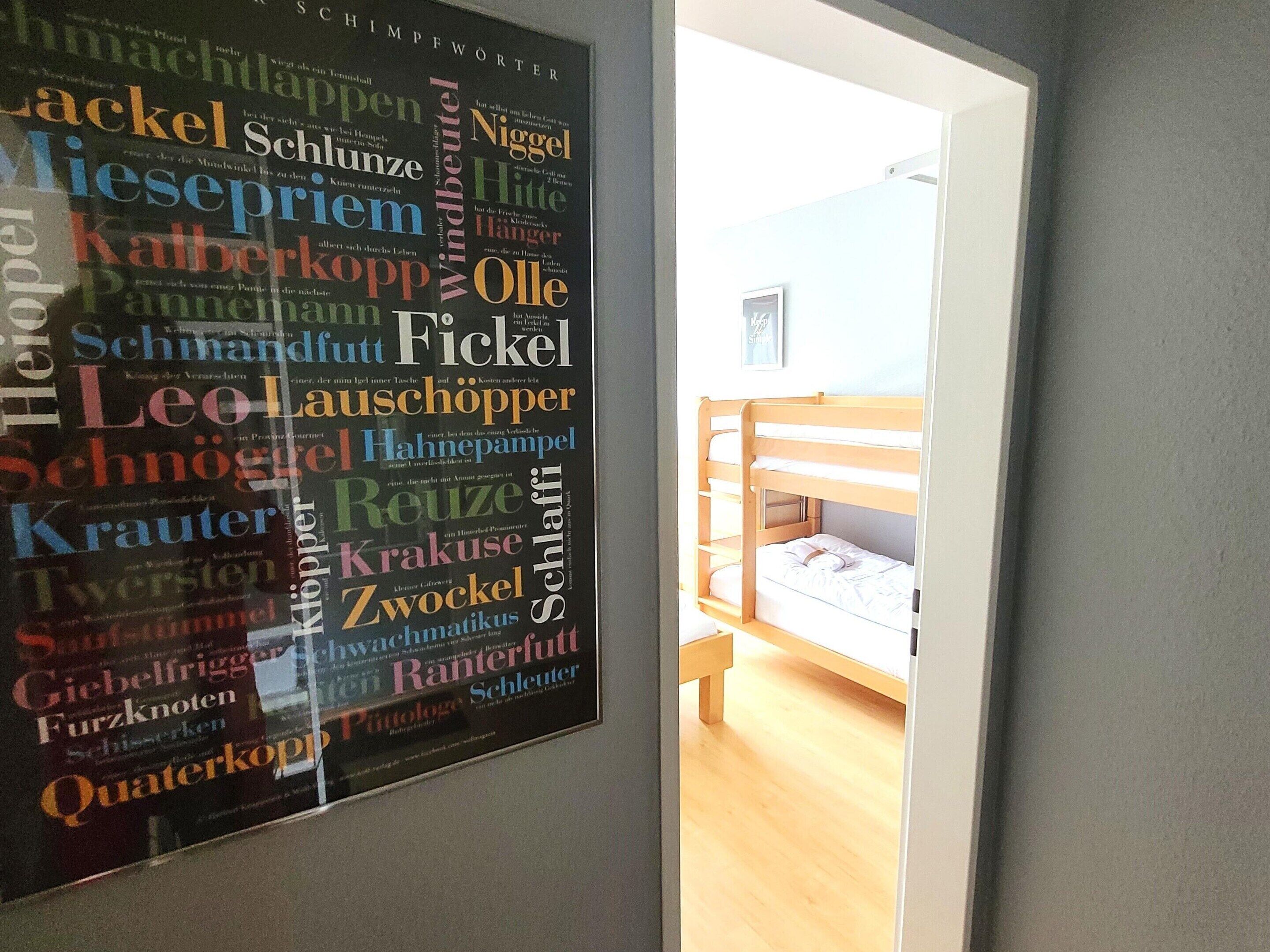 A room with a bunk bed and a wall poster with various words.