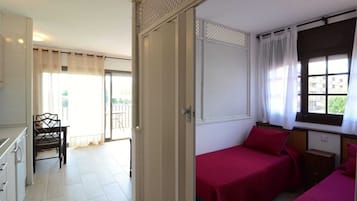 A room with two beds, a dining table, and a chair.