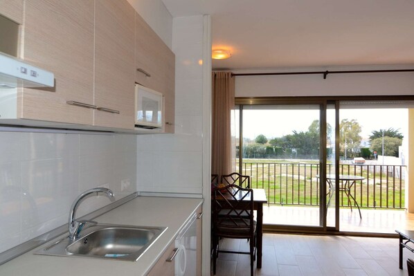 A modern kitchen with a built-in microwave, a sink, and a dining area with a table and chairs.