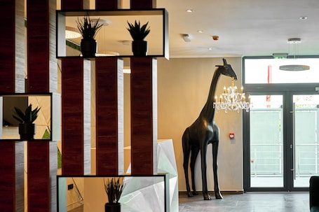 Un interior moderno con una gran escultura de jirafa, paneles de madera y una araña.