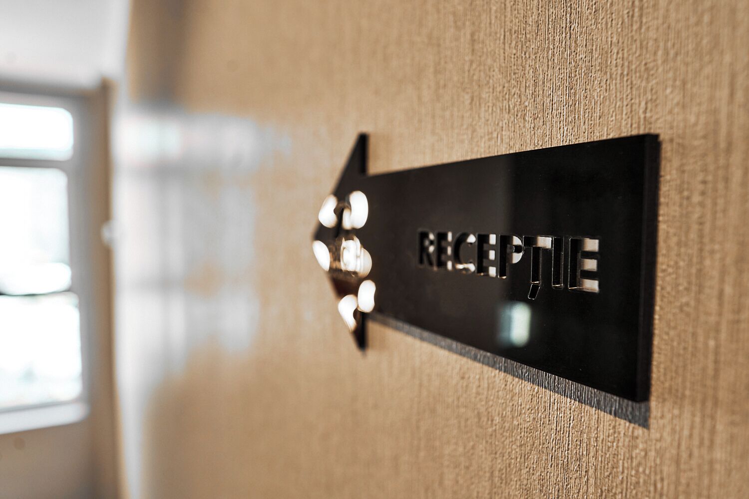 A black sign with 'RECEPTION' in metallic letters, mounted on a textured wall.