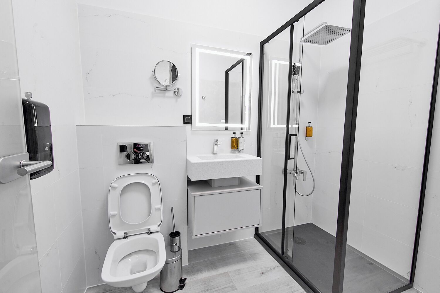 Ein modernes Badezimmer mit Toilette, Waschbecken, Spiegel und Duschkabine.