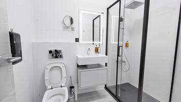 Ein modernes Badezimmer mit Toilette, Waschbecken, Spiegel und Duschkabine.