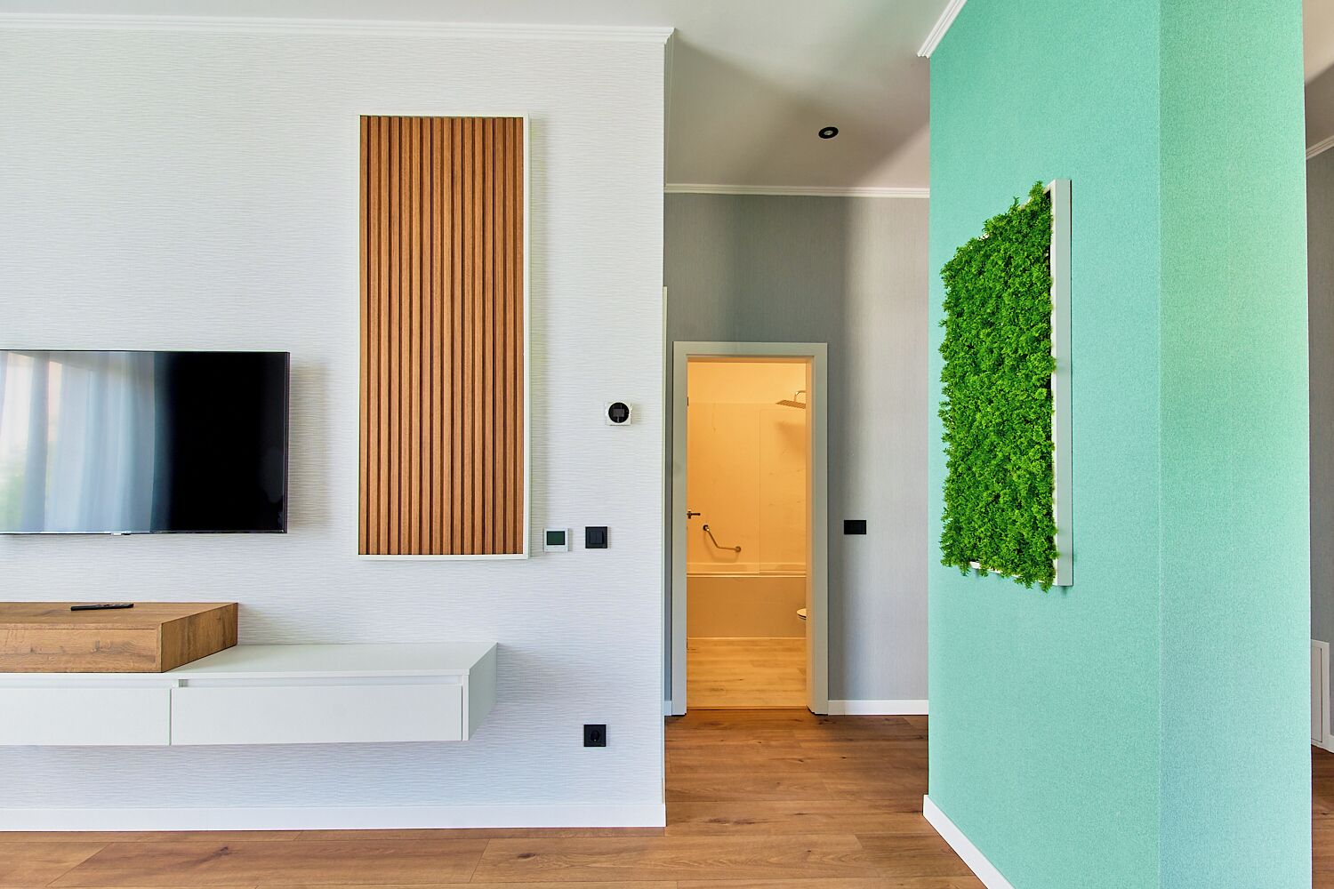 Un soggiorno moderno con una televisione a schermo piatto, un pannello in legno, una parete verde con giardino verticale e una panca in legno.