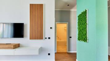 Un soggiorno moderno con una televisione a schermo piatto, un pannello in legno, una parete verde con giardino verticale e una panca in legno.